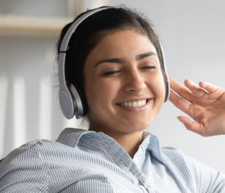 A woman smiling with headphones on enjoying entertainment through her Unlimited Antenna.