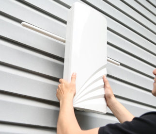 A person mounting an Unlimited Antenna on the side of their home. 