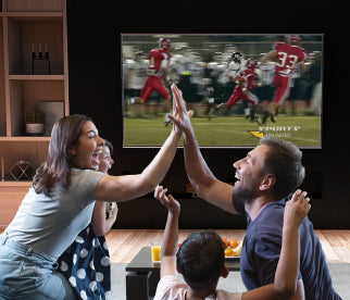 A couple sitting in front of a TV watching football through their Unlimited Antenna connection with their kids and high-fiving one another.