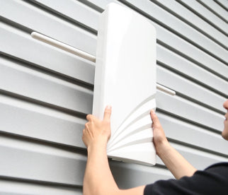 A person mounting an Unlimited Antenna on the side of their home.