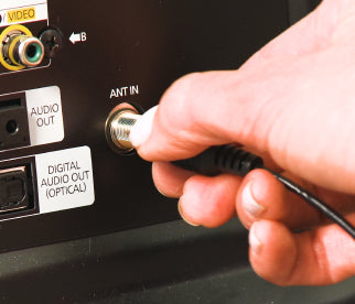 A person plugging their Unlimited Antenna signal booster into the back of their TV. 